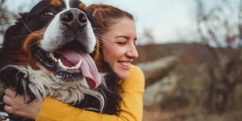 Glad kvinna kramar en stor hund. En perfekt storlek för en trogen vän, som en del av en storleksguide hundraser.