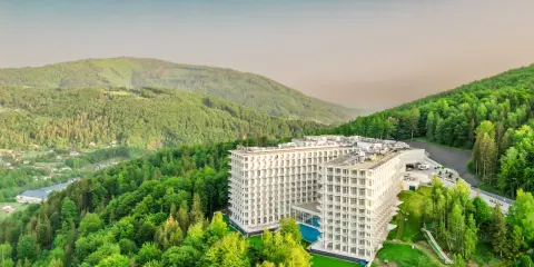 Nowoczesny hotel wtopiony w zieleń gór, przypominający kształtem górę czaszki.