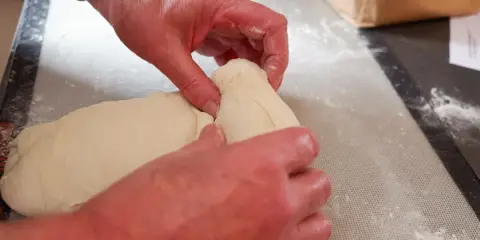 Mains travaillant la pâte à pain, étape d'autolyse. La pâte est souple et prête à être façonnée.