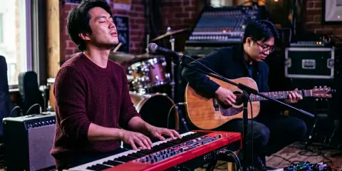 Deux musiciens jouent sur scène. L'un au piano rouge, l'autre à la guitare acoustique. Parfait pour un blog musique.