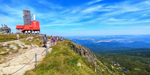 Grupa turystów wędruje ścieżką na Łabski Szczyt, podziwiając rozległą panoramę gór i dolin.
