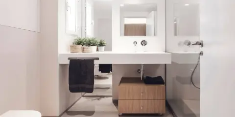 Baño moderno con lavabo flotante, mueble de madera y plantas. Ideal para quienes buscan reformar baño precio.