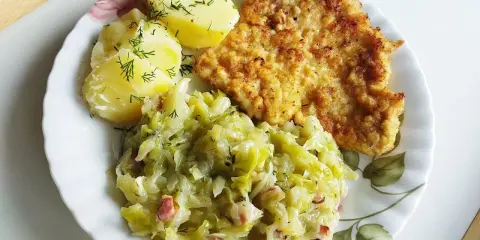 Kotlet schabowy z ziemniakami i młodą kapustą zasmażaną z boczkiem.