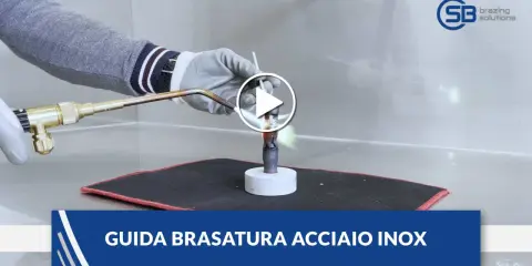Guida alla brasatura ferro: un operatore con guanti usa una torcia per riscaldare un tubo metallico, mostrando la fiamma viva.