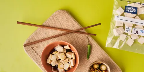 Vorbereitung für tofu einfrieren: gewürfelter Tofu in Schüssel mit Soße, daneben Stäbchen, Chili und ein Gefrierbeutel mit Tofuwürfeln.