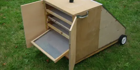 Un sechoir solaire diy en bois, avec des étagères et une porte ouverte sur un tamis. Idéal pour sécher des herbes ou des fruits au soleil.