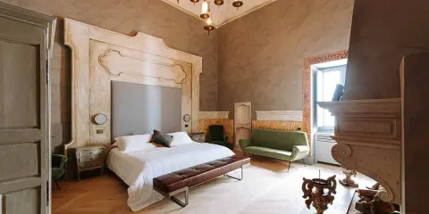 Ett lyxigt sovrum med en stor säng, grön soffa och en imponerande eldstad. Perfekt hotell inredning inspiration för ett elegant hem.