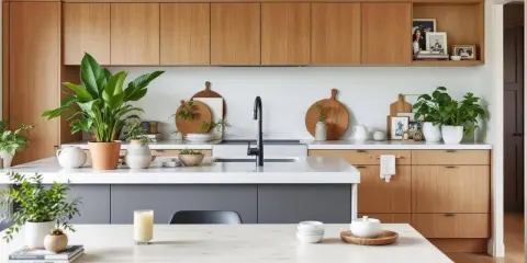 Élégante déco cuisine moderne chic avec armoires en bois, îlot gris, plantes vertes et vaisselle en bois.