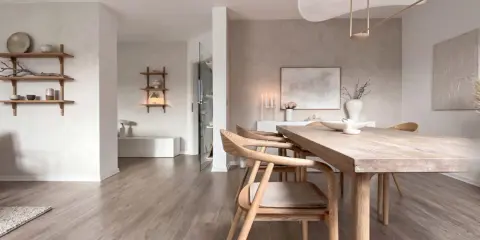 Interni in stile wabi sabi con tavolo in legno grezzo, sedie in legno chiaro e decorazioni minimaliste.