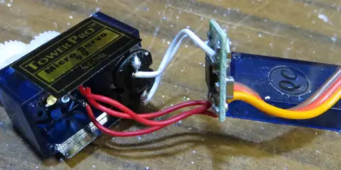 Ein Tower Pro Micro Servo mit Zahnrädern und einem 1m Verlängerungskabel, verbunden über eine kleine Platine.