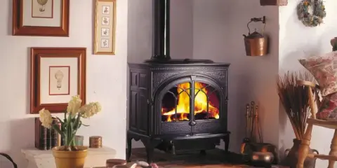 Przytulny pokój z palącym się piecem kaflowym, który jest idealnym rozwiązaniem, jak oświetlić pomieszczenie bez prądu.
