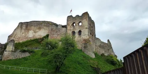 Zamek Czorsztyn, majestatyczna ruina na wzgórzu, z polską flagą powiewającą na wieży.