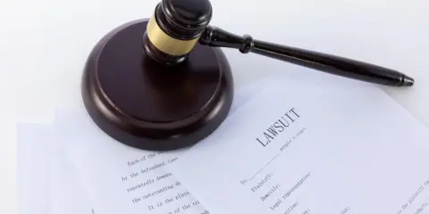 Młotek sędziowski na dokumentach sądowych, w tym na formularzu "LAWSUIT". Może posłużyć jako wzór wniosku o alimenty bez rozwodu.