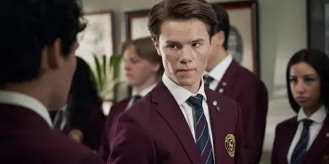 Ungdomar i skoluniformer, en av young royals skådespelare tittar intensivt.