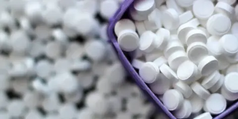 Mnóstwo białych tabletek, w tym w fioletowym pojemniku. To słodzik, który zawiera aspartam.