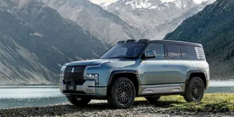 Le byd yangwang u8, un SUV imposant, se tient au bord d'un lac, avec des montagnes enneigées en arrière-plan.