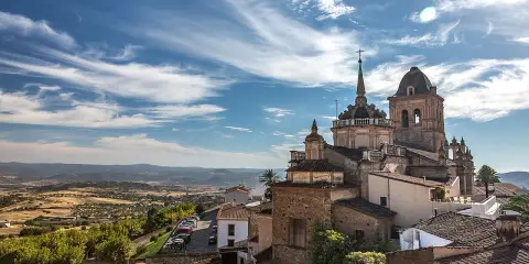 Blick auf die historische Stadt Jerez de los Caballeros mit ihren beeindruckenden Kirchtürmen unter einem dramatischen Himmel.