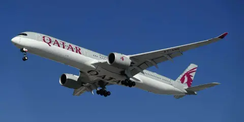 Samolot Qatar Airways z wysuniętym podwoziem, gotowy do lądowania. Idealny do podróży z bagażem podręcznym.