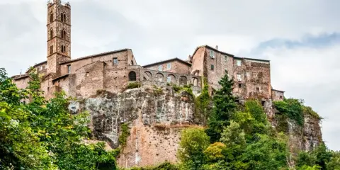 Un borgo medievale arroccato su una rupe, con un'alta torre campanaria. Un esempio dei borghi più belli del Lazio, immerso nel verde.