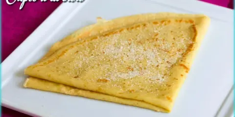 Crêpes à la bière, dorées et saupoudrées de sucre, sur une assiette blanche. Un délice gourmand !