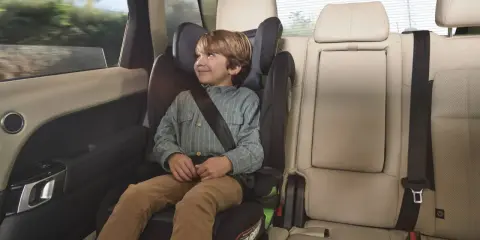 Niño sonriente en una silla de coche grupo 3 edad, viajando seguro y cómodo en el asiento trasero de un vehículo.