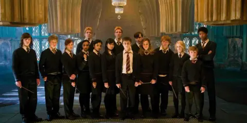Grupa uczniów z domu Hufflepuff, w tym Harry Potter, stoi w eleganckiej sali.