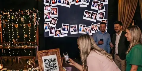 Eine Frau scannt mit ihrem Handy einen QR-Code für eine Photowall. Eine tolle Idee für ein Hochzeitsprogramm mit vielen Erinnerungsfotos.