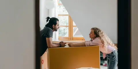 Par diskuterar flytten utomlands, omgivna av flyttkartonger. En checklista för flytten är troligen nära till hands.
