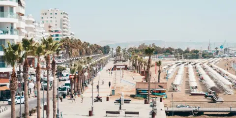 Promenada w Larnace z palmami, białymi budynkami i plażą pełną leżaków. Idealne miejsce, by zobaczyć, co oferuje Larnaka.