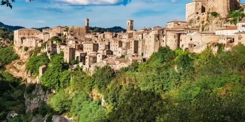 Un affascinante borgo toscano da visitare, arroccato su una rupe tufacea, con case in pietra e torri che si stagliano contro il cielo azzurro.