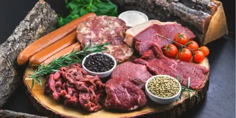 Mięso wołowe, kiełbaski, kotlety i przyprawy na desce. Idealne składniki dla diety carnivore.
