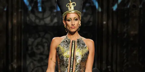 A model wears a striking Nefertiti-inspired headdress and ornate gold and black gown, showcasing the bold vision of Egyptian fashion designers.