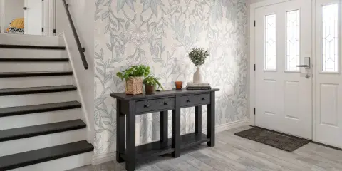 Hall med trappa och en konsol med växter. Vacker morris tapet inspiration med blommor och bladverk.