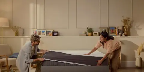 Ein Paar zieht einen Bezug über eine Emma Matratze. So einfach, dass man sie sofort benutzen kann!