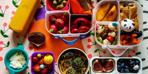 Kolorowy lunchbox z owocami, warzywami, kanapką i słodkościami to idealne szybkie śniadanie dla dzieci.
