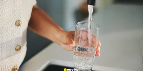 Ręka nalewa wodę do szklanki. Zastanawiasz się, kiedy skończy się woda pitna? Dbajmy o zasoby.