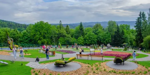W parku krajobrazowym z kwiecistymi rabatami i rzeźbami z roślin, ludzie spacerują pośród zieleni. Ile się idzie, tyle piękna!