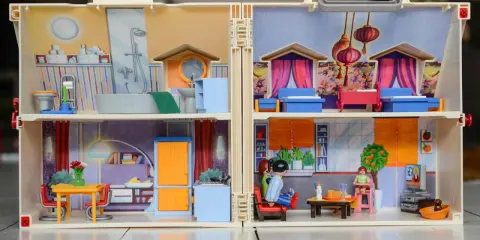Casa de muñecas con habitaciones detalladas, mostrando actividades de la vida diaria ejemplos como baño, cocina y sala.