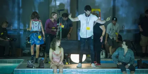 Reżyser instruuje aktorkę siedzącą w basenie. Wszyscy są **trzy kroki od siebie**, tworząc scenę filmową.