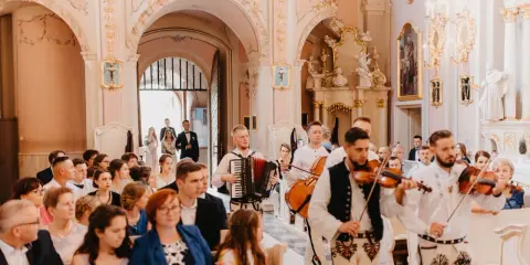 Muzycy grają piosenkę dla świadków w kościele. W tle para młoda wchodzi do świątyni.