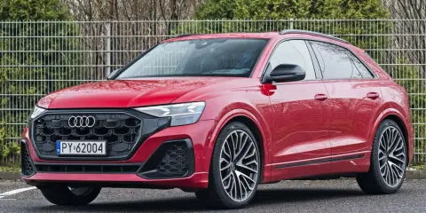 Czerwony Audi RS Q8 z czarnymi felgami stoi na parkingu.