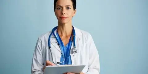 Medico con camice bianco e stetoscopio, appunti su cartella clinica. Ricerca sulla sindrome di Laron.