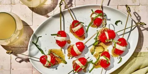 Szabli z pomidorkami koktajlowymi, mozzarellą i bazylią na białym talerzu.