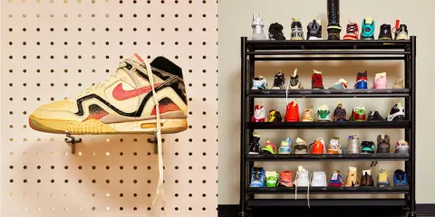 Eine Sammlung von Sneakern, darunter ein einzelner Schuh an einer Lochwand und viele weitere auf einem Regal. Ein Blick auf die Vielfalt der Nike Kollaborationen.