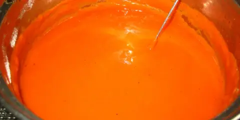Gęsty, pomarańczowy sos pomidorowy do gołąbków w metalowym garnku, z widoczną igłą termometru.