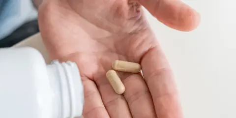 Dwie kapsułki probiotyku na dłoni, gotowe do zażycia przed wyjazdem do Turcji.