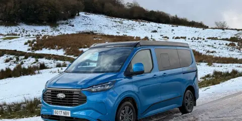 Furgoneta phev azul aparcada en un camino nevado, lista para una aventura invernal.