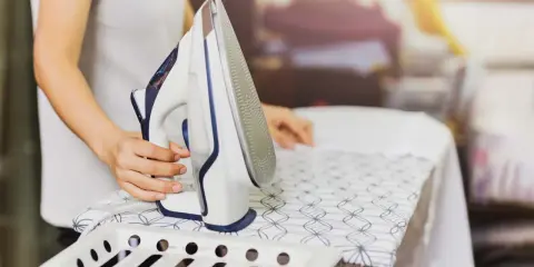 Persona plancha un vestido de satén con cuidado en una tabla de planchar.