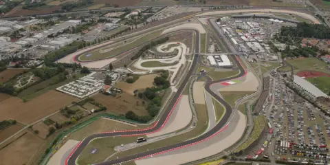 Vista aerea del circuito di Misano, noto anche come circuito San Marino, con tribune piene di spettatori e un vasto parcheggio.