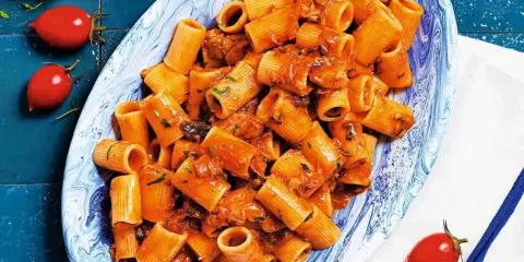Rigatoni conditi con un sugo rosso saporito, ricco di tonno e erbe aromatiche. Un piatto di pasta al tonno invitante.